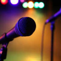 This is a picture taken of a pair of microphones sitting on a dimly lit stage. 