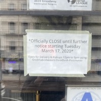 Window for Buddha Taco Bar with 2 signs. Top sign with text, "...NIGHTS at Buddha Taco Bar: every week starting at 8:30: NYC Trivia League" and bottom sign with text, "*Officially CLOSE until further notice starting Tuesday March 17, 2020*: Open for Delivery & Pickups 12pm to 9pm using GrubHub-Ubereats-DoorDash-Postmates"
