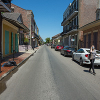 A masked person walking down an empty street.