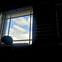 This is a picture taken from the inside of a dark room of the view of the sky through a window. 