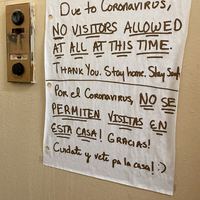 A hand written sign in English and Spanish that says "Due to Coronavirus, no visitors allowed at all at this time. Thank you, stay home, stay safe."