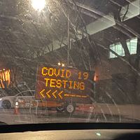 Electronic construction work sign with text, "COVID 19 TESTING" and an arrow pointing left. 