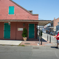 A person crossing a vacant street by a red building.