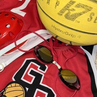 Red sports jersey with goggles and yellow water polo ball.