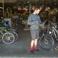 A person holding a laptop in a bike store.