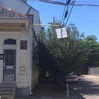 Corner of a street with an older house with a sign in the door with text, "BALANCE? Where's The Fairness?" with a photo of a scale and it tipping to one side.  Another sign hanging from a pole with text, "How Many Thousands More Americans Will Die....Due to Trump's Horrific Arrogance?"
