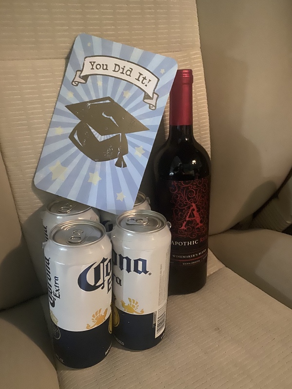 Multiple cans, a bottle and a card in a carseat.