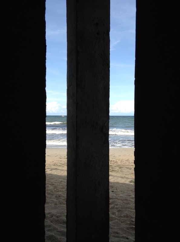 A view of the sea behind three bars. 