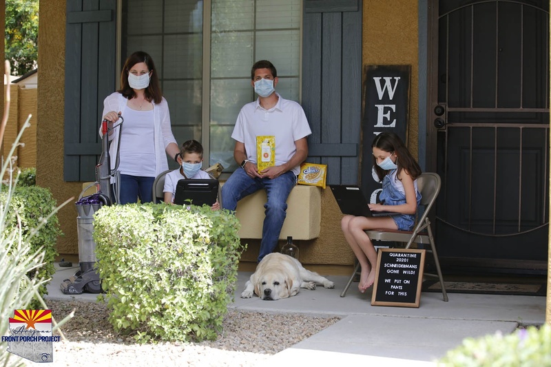A family posing on their front porch wearing masks. 