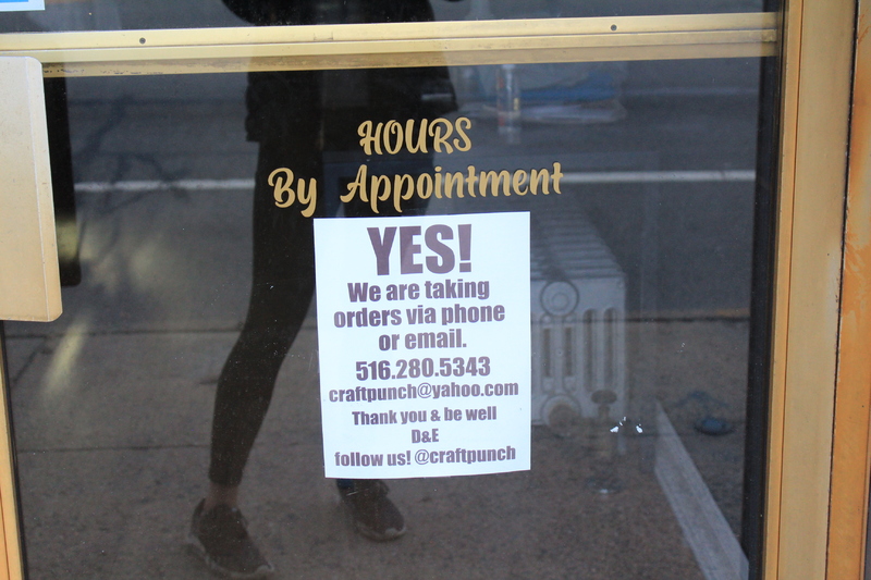 A window with the words "Hours by appointment" on it,  below is a sign that says: "Yes, we are taking orders via phone or e-mail" with the company's phone number, e-mail, and Instagram handle on the sign. 