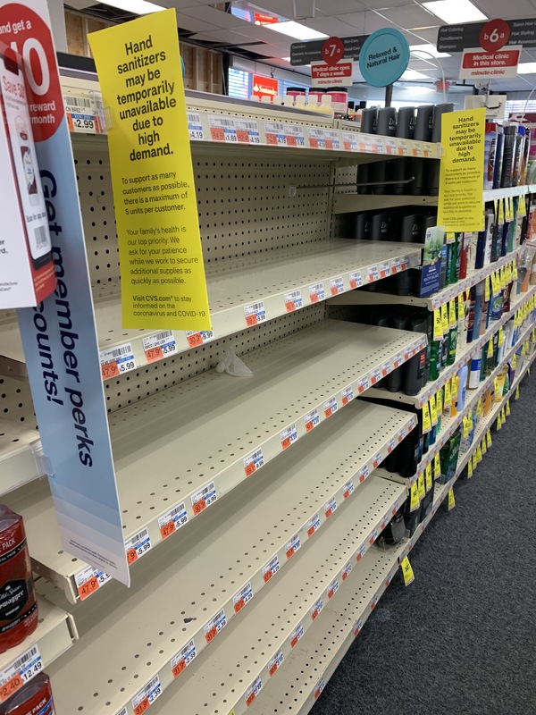 An empty row of shelves with yellow signs taped on them.