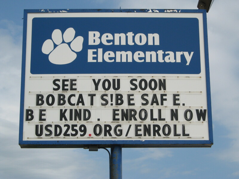 A Elementary school sign reading "See you soon Bobcats! Be safe. Be kind. Enroll now. USD259.org/enroll".