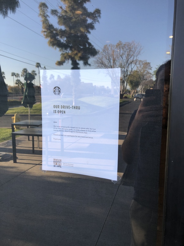 A piece of paper is taped to the inside of a door that says: Our Drive-thru is open.