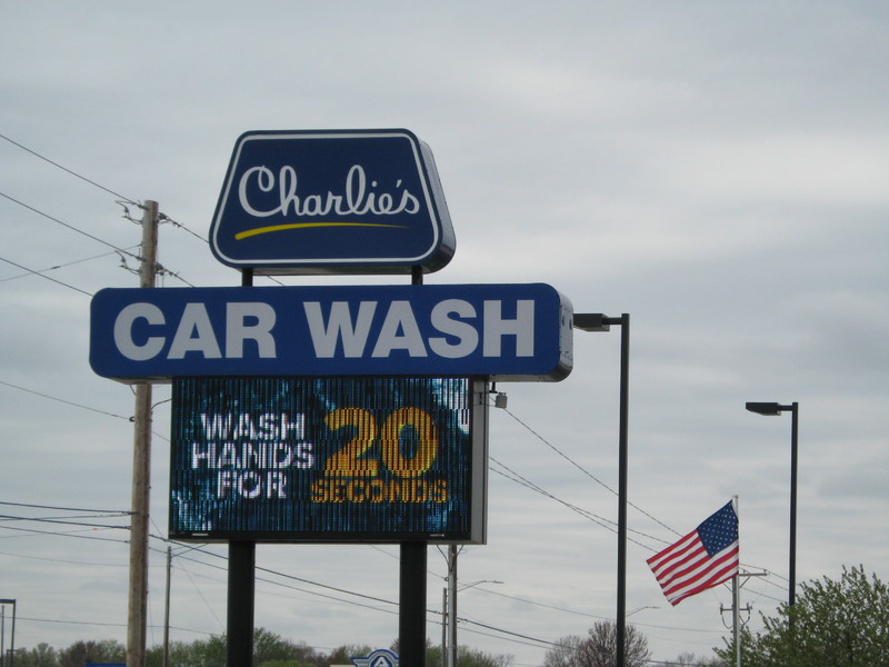 Blue sign for "Charlie's Car Wash" in Wichita, Kansas with white and yellow text saying, " WASH HANDS FOR 20 SECONDS." 