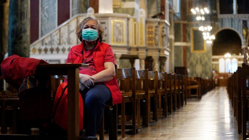 A masked woman sitting in church. 