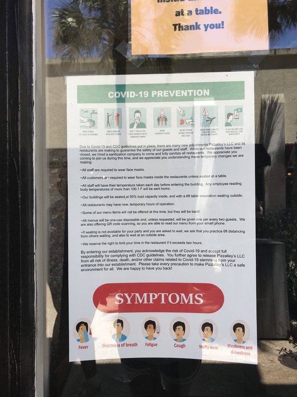 This is a picture of a sign in the window of a business which explains how to prevent the spread of COVID-19. 