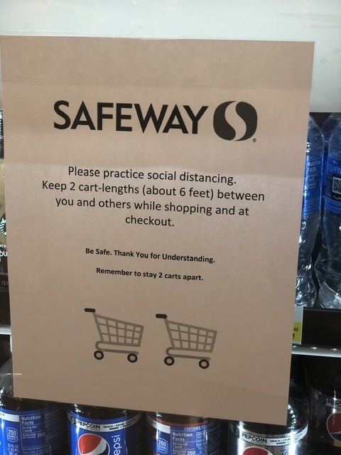 A piece of paper is taped on the front of a vending machine that talks about practicing social distancing while visiting the grocery store. 