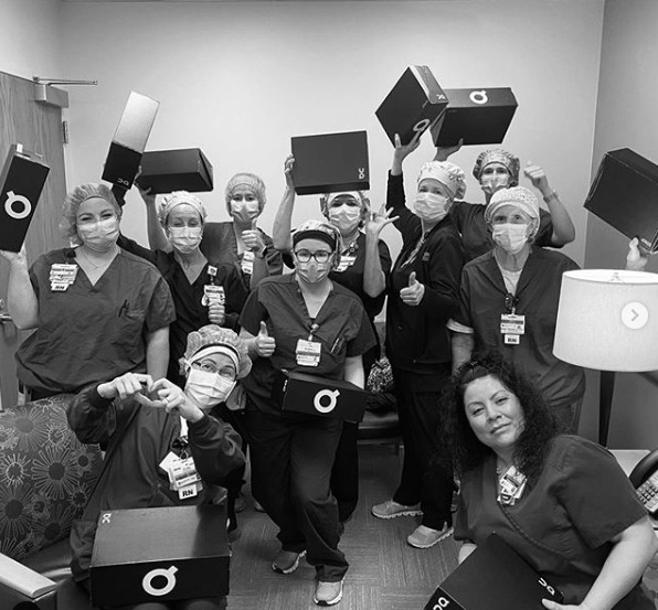 Black and white photo of nurses holding ON running shoe boxes.