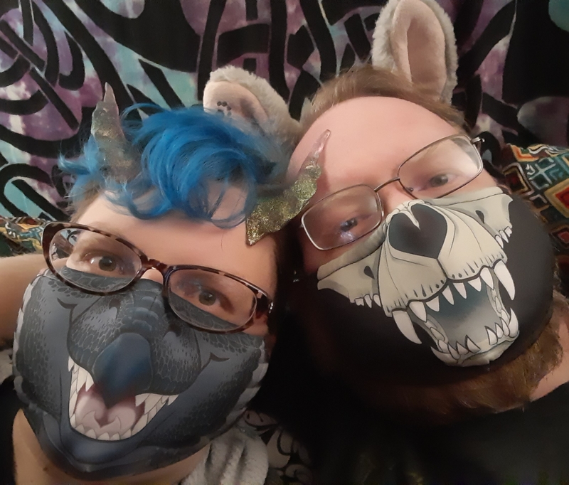 Two people posing with animal themed face masks. 