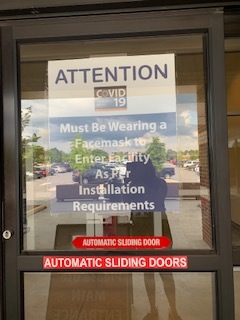 A picture of a sign posted on the door to the entrance to a military building at Fort Bragg, North Carolina which reads: "Attention! Must be wearing a face mask to enter facility as per installation requirements."