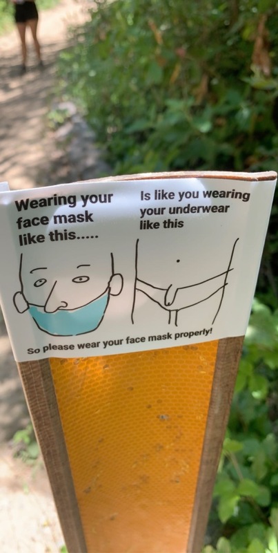This is a picture of a piece of paper taped to a pole outside. There are two images drawn on the paper, one of a man wearing a mask with his nose exposed with the caption "wearing your face mask like this...", and another of a person with their underwear pulled down to expose their genitals under which is written "Is like wearing your underwear like this." A further caption reads "So please wear your face mask properly!" 