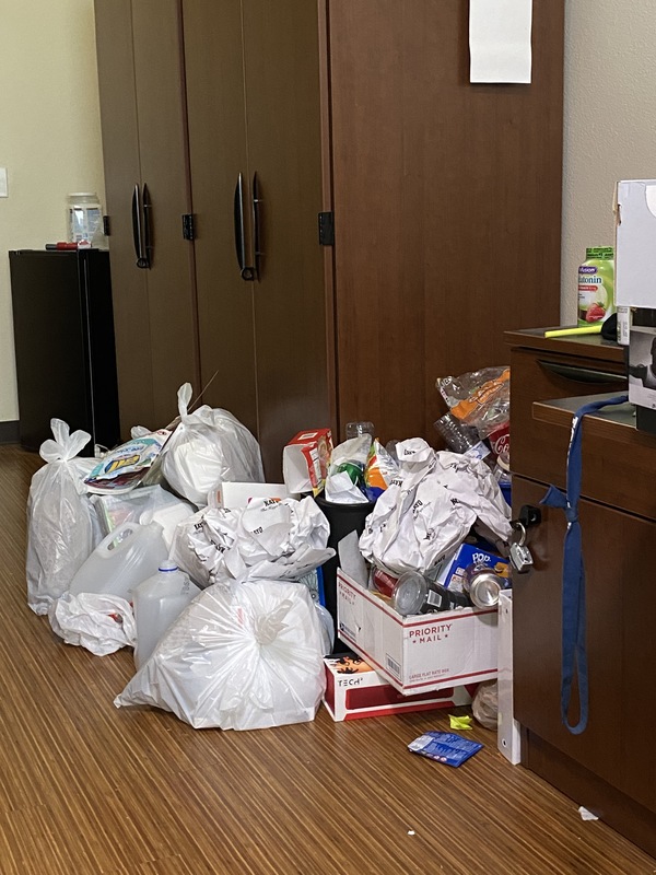 A hotel room that has multiple bags of trash. 