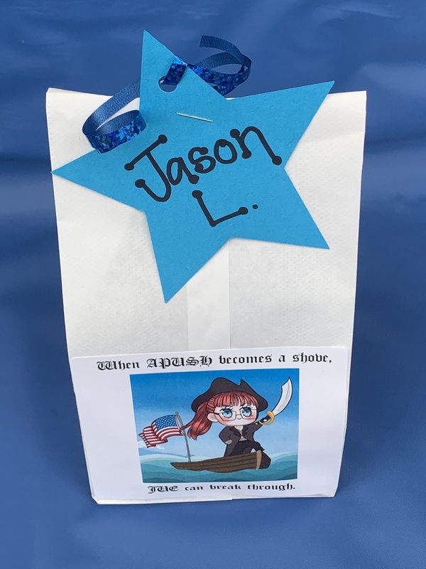 This is a picture of a gift bag for "Justin L", which has a cartoon drawing of a female pirate pasted to the side.