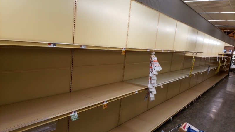 An aisle in a grocery store that has empty shelves. 