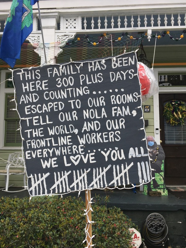This is a picture taken of a sign in front of a person's house. The sign reads: "This family has been here 300 plus days and counting...... Escaped to our rooms. Tell our Nola fam, the world, and our front line workers everywhere...... WE LOVE YOU ALL!" 28 tally marks are drawn at the bottom of the sign. 