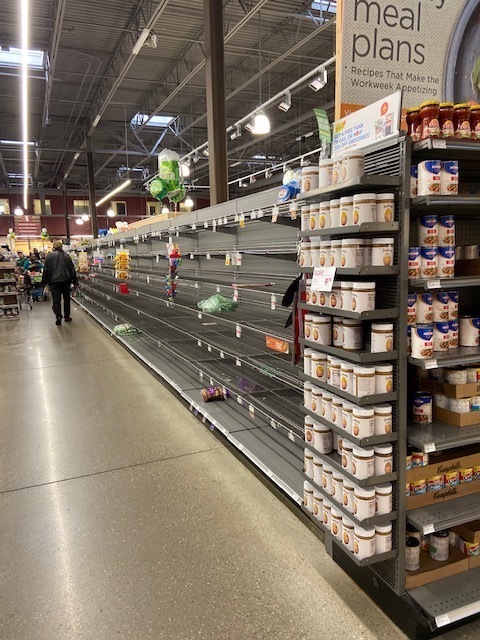 An aisle in a grocery store with empty shelves. 