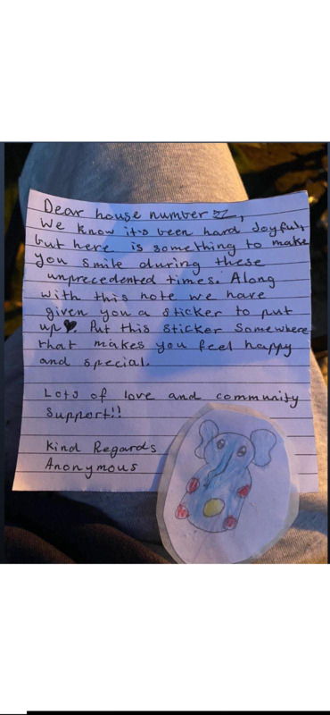Picture of a letter left with an elephant sticker at someone's doorstep. The letter states that the writer knows times have been hard lately, so hopefully the sticker included might brighten the recipients day when they see it. A form of community support. 