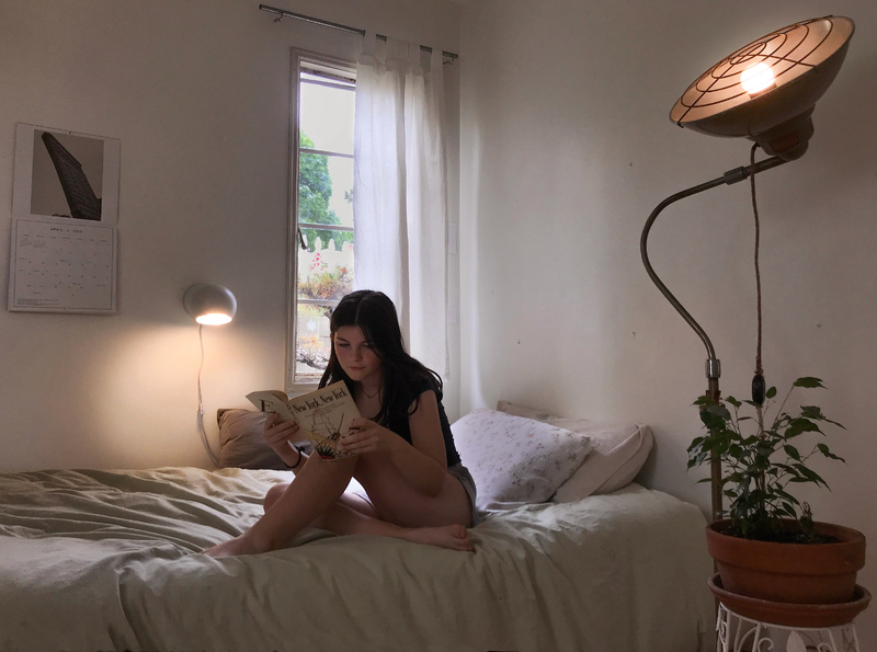 A person sitting on a bed reading a book. 