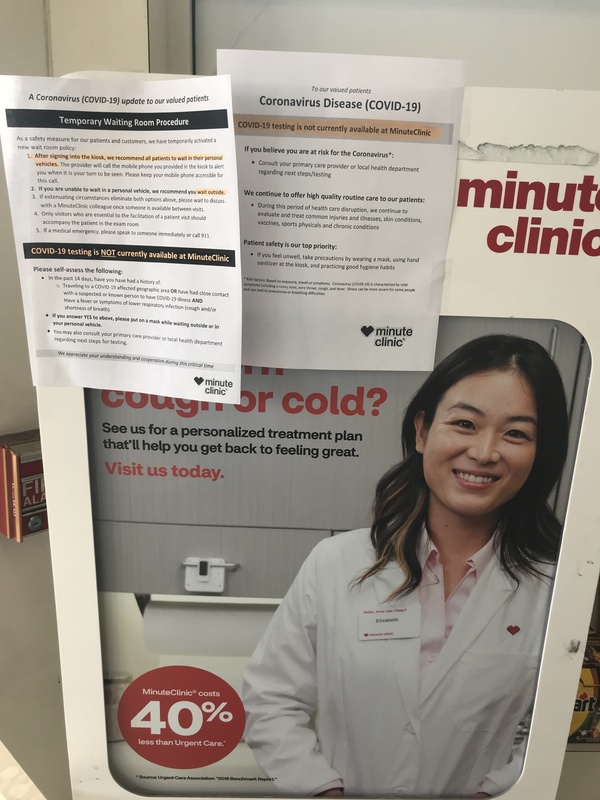 Information papers on a sign in CVS that talk about waiting room procedures due to COVID-19, CVS is currently not doing COVID-19 testing, and more information about COVID-19. 