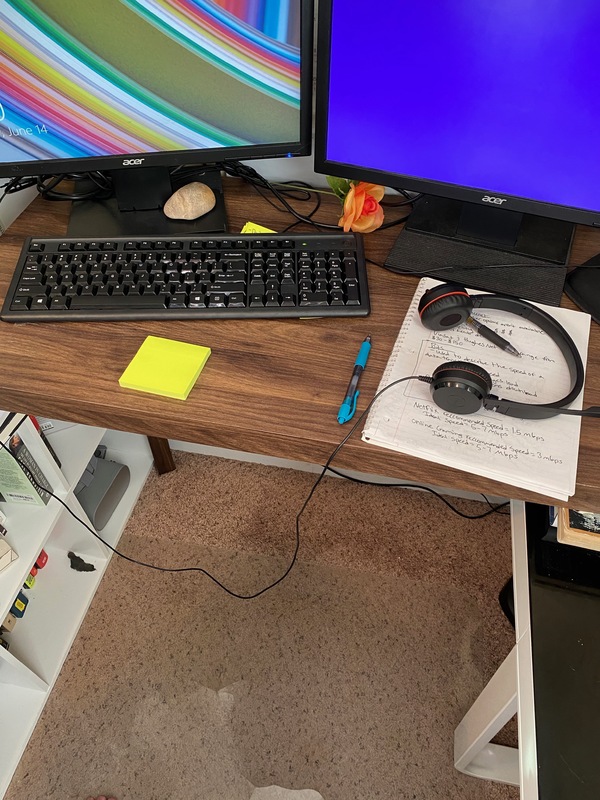 A desk sit up for remote work with two monitors, keyboard, and headset.