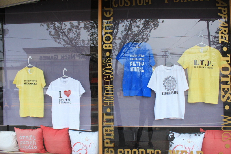 A shop window with various Covid-19 themed t-shirts on display. 