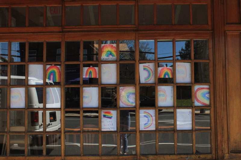 Seventeen rainbow drawings placed in a window. 