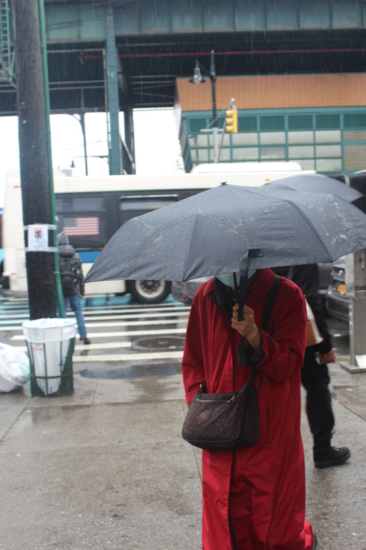 A person with a mask on holding an umbrella. 