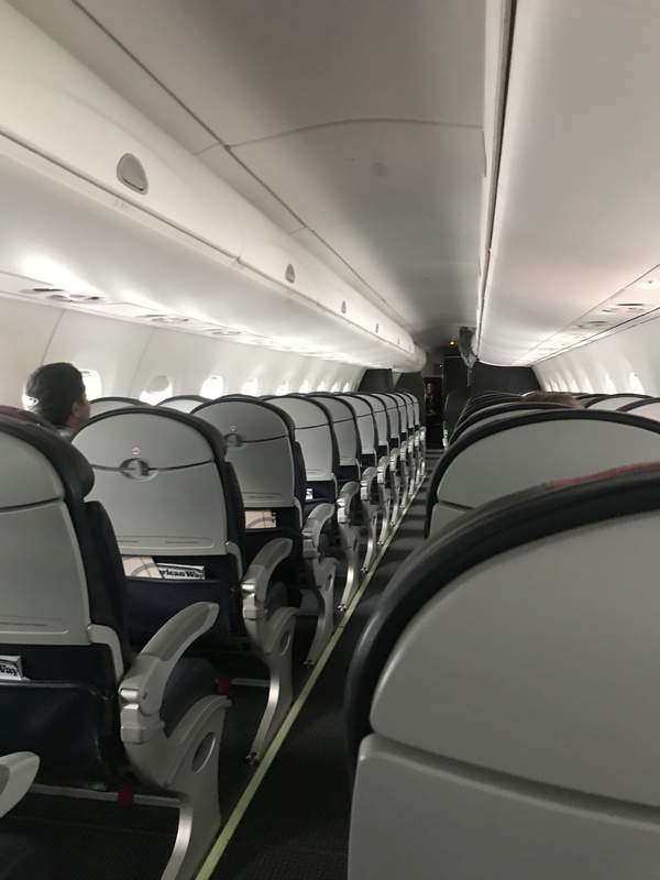 Inside of a flight cabin, there are only three people sitting in seats. 