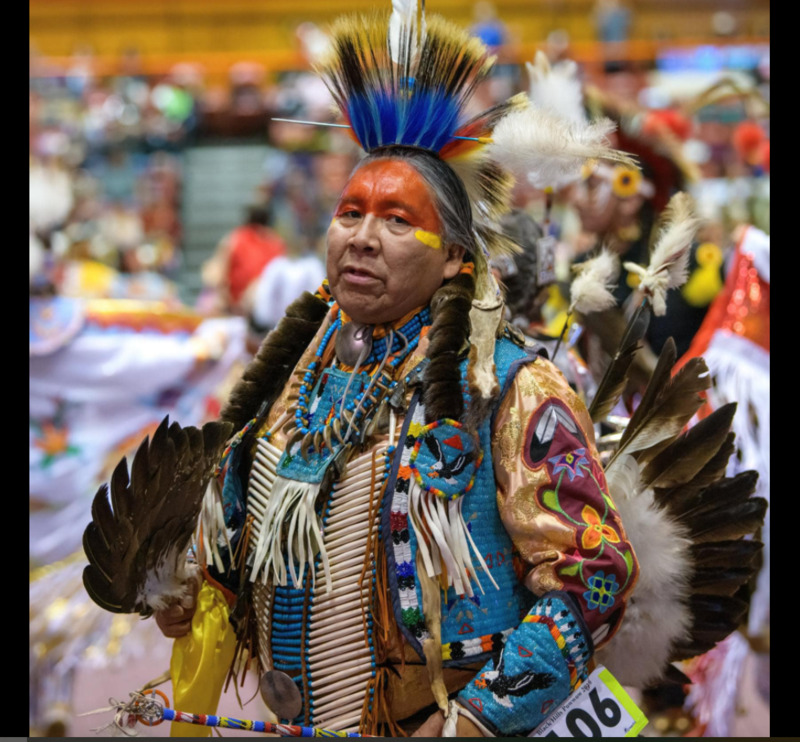 This is a picture of a Native American man dressed in traditional ceremonial clothing, likely at a powwow. 