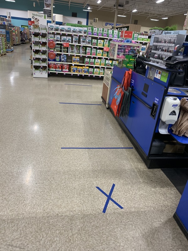 A store with blue tape of the floor indicating social distance. 