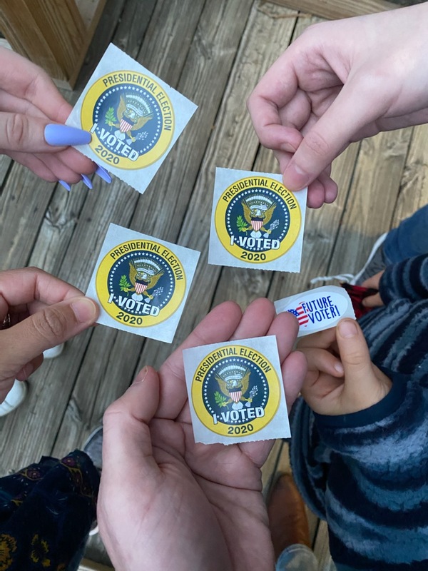 Picture of five people holding stickers that read "Presidential Election 2020: I voted!" and "Future Voter!". 