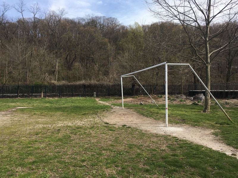 A soccer goal without a net in an empty field.
