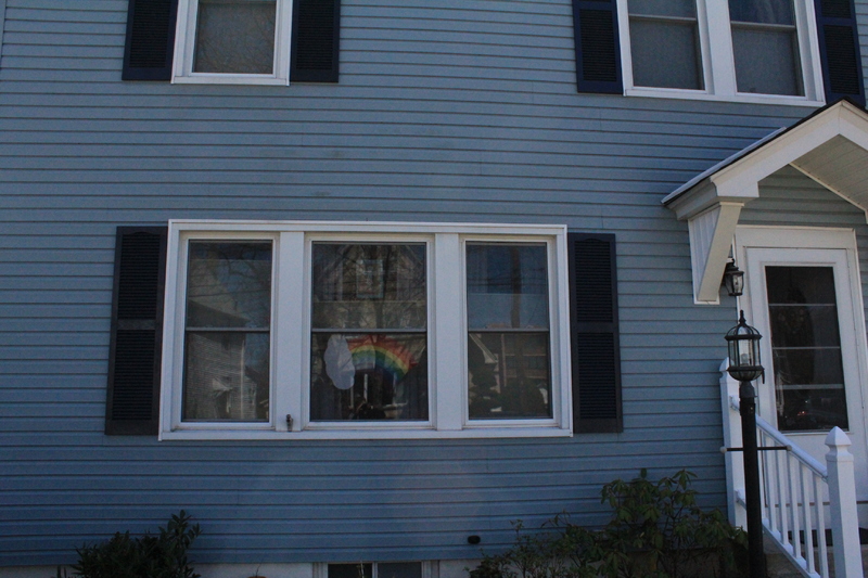 Residential house with a rainbow placed in a front window. 