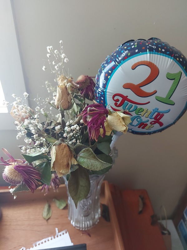 A picture of a balloon and a vase of flowers purchased for someone's 21st birthday. 