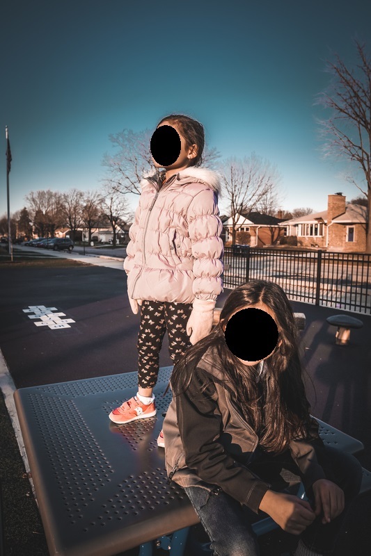 Two children in winter coats standing outdoors.