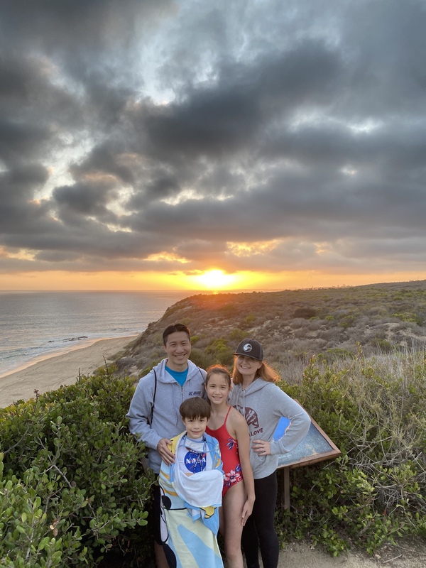 This is a picture of a family of four at the beach during sunset. 