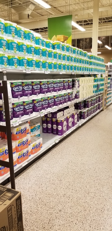 A toilet paper aisle in a grocery store that is fully stocked. 