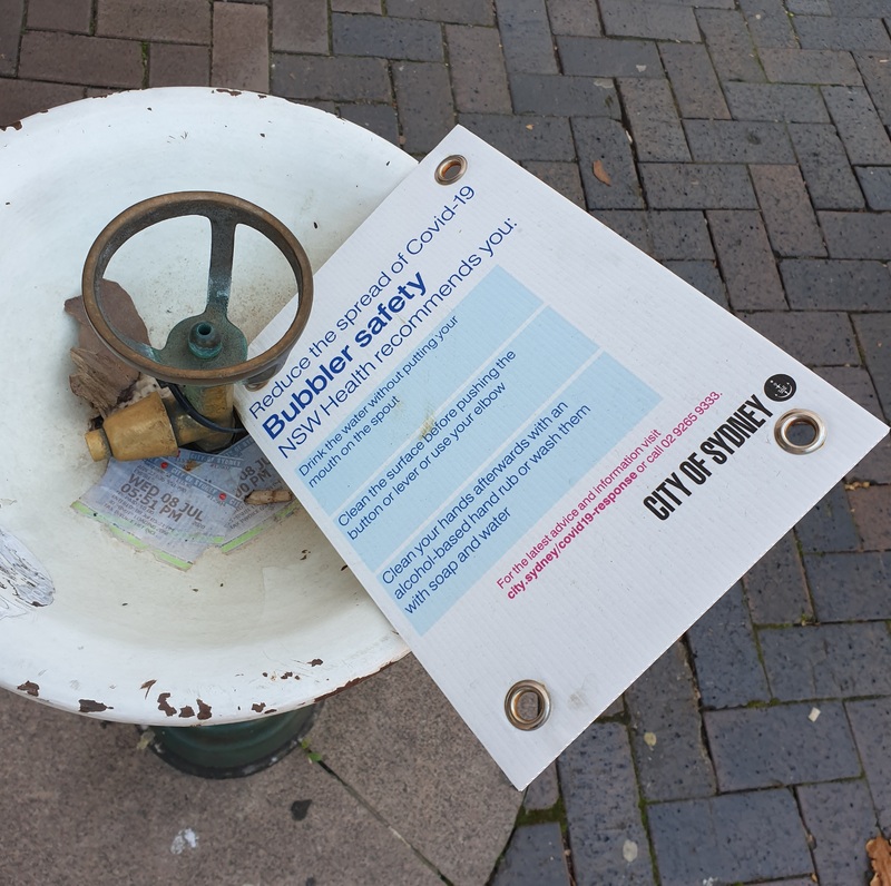 A sign on a water fountain advising how to stay safe while drinking from the fountain.
