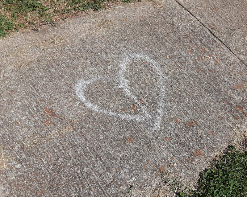 A heart drawn with white chalk on a sidewalk.