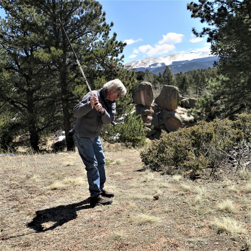 A man pretending to play golf by using a hiking pole and a pine cone at Mueller State Park. 